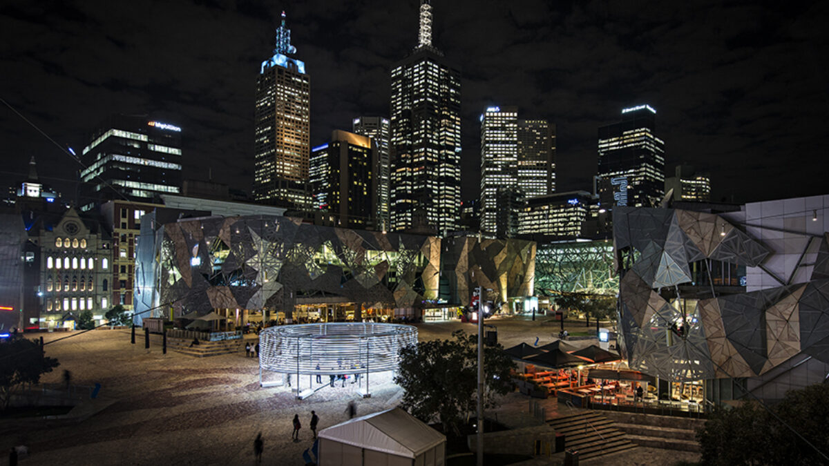 Circular light installation in front of Melbourne skyline